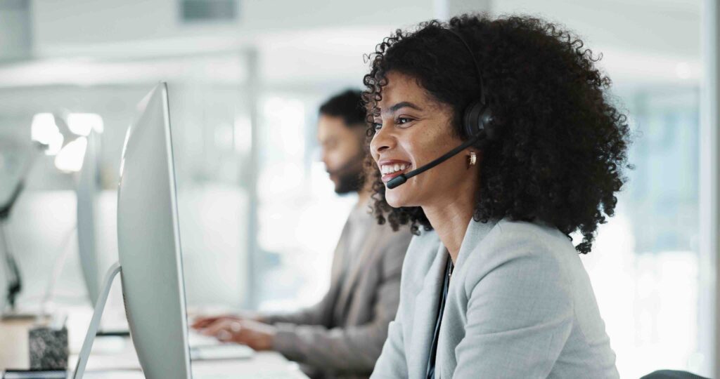 Happy woman working for an MSP on the phone and in front of a computer, dealing with IT questions